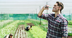 Man, farmer or drinking with water in greenhouse for agriculture or natural sustainability. Thirsty, male person or farming with liquid or food production for hydration, agro business or conservation