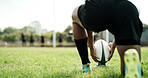 Rugby ball, hands and player on field with kick, start game or match for competition or challenge. Sport, person and football on tee for tournament, score or accuracy practice with fitness and space