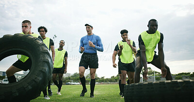 Buy stock photo Fitness, coach and men with tire on field, strength challenge and instructions for sports training. Coaching, instructor or rugby team with exercise for muscle development, active or weightlifting