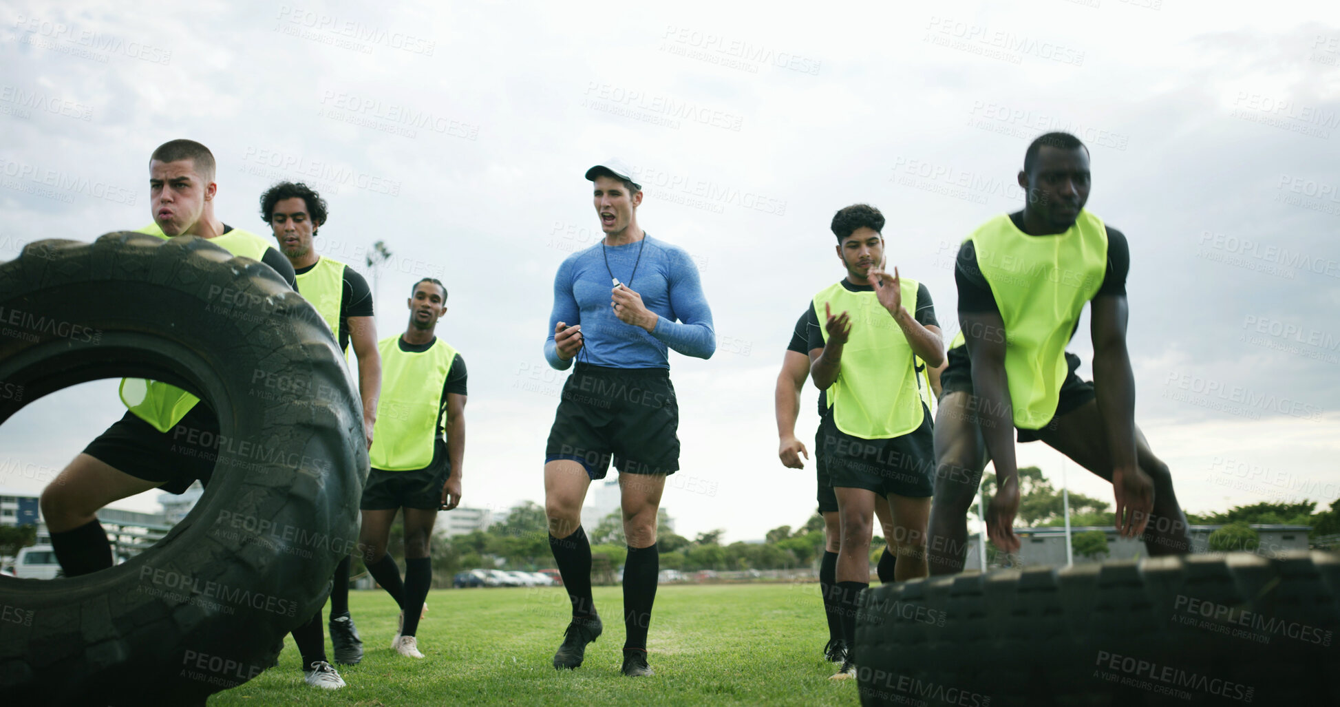 Buy stock photo Fitness, coach and men with tire on field, strength challenge and instructions for sports training. Coaching, instructor or rugby team with exercise for muscle development, active or weightlifting
