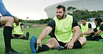 Coach, stretching or man with practice on field, sports training or warm up routine for preparation. Outdoor, instructor or people with leg exercise for mobility, rugby club or getting ready for game
