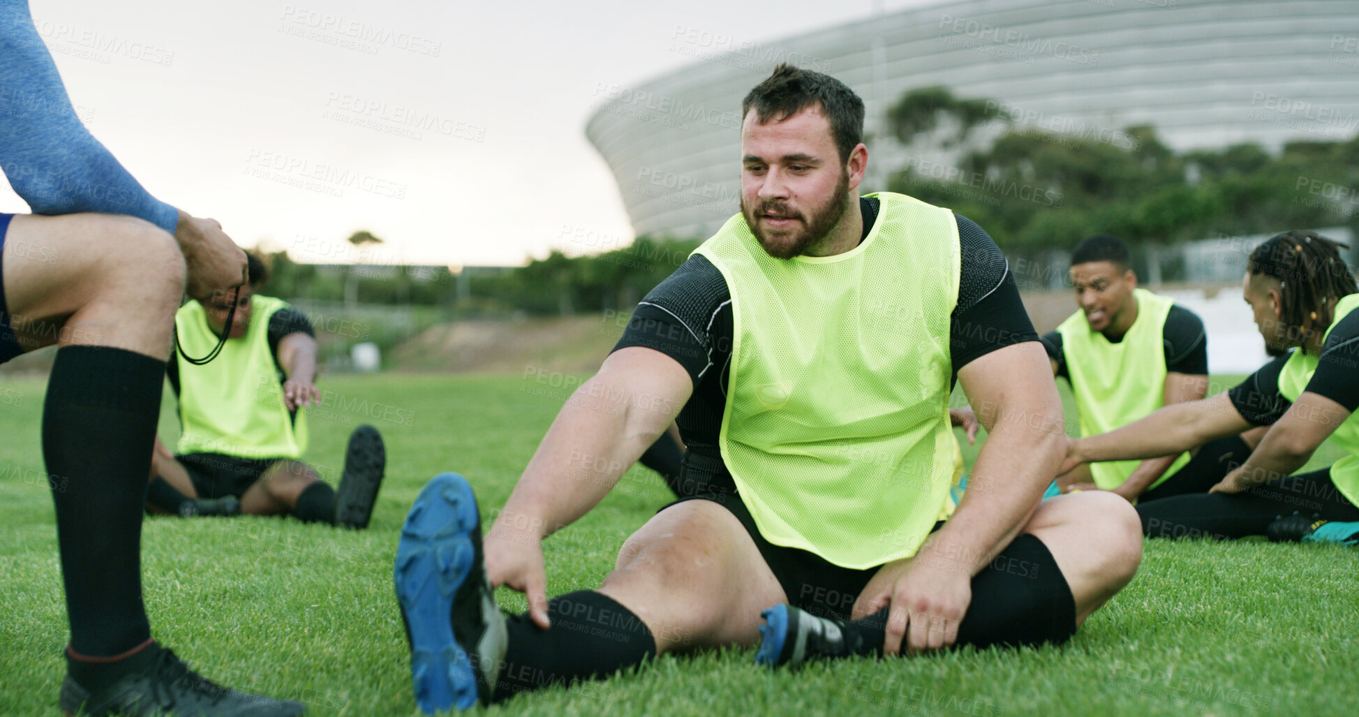 Buy stock photo Coach, stretching or man with practice on field, sports training or warm up routine for preparation. Outdoor, instructor or people with leg exercise for mobility, rugby club or getting ready for game