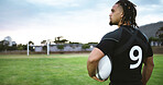 Man, thinking or rugby player on field with ball, game plan or contemplation for fitness practice. Back, athlete or person outdoor with equipment for match, vision or brainstorming for sport tactics.