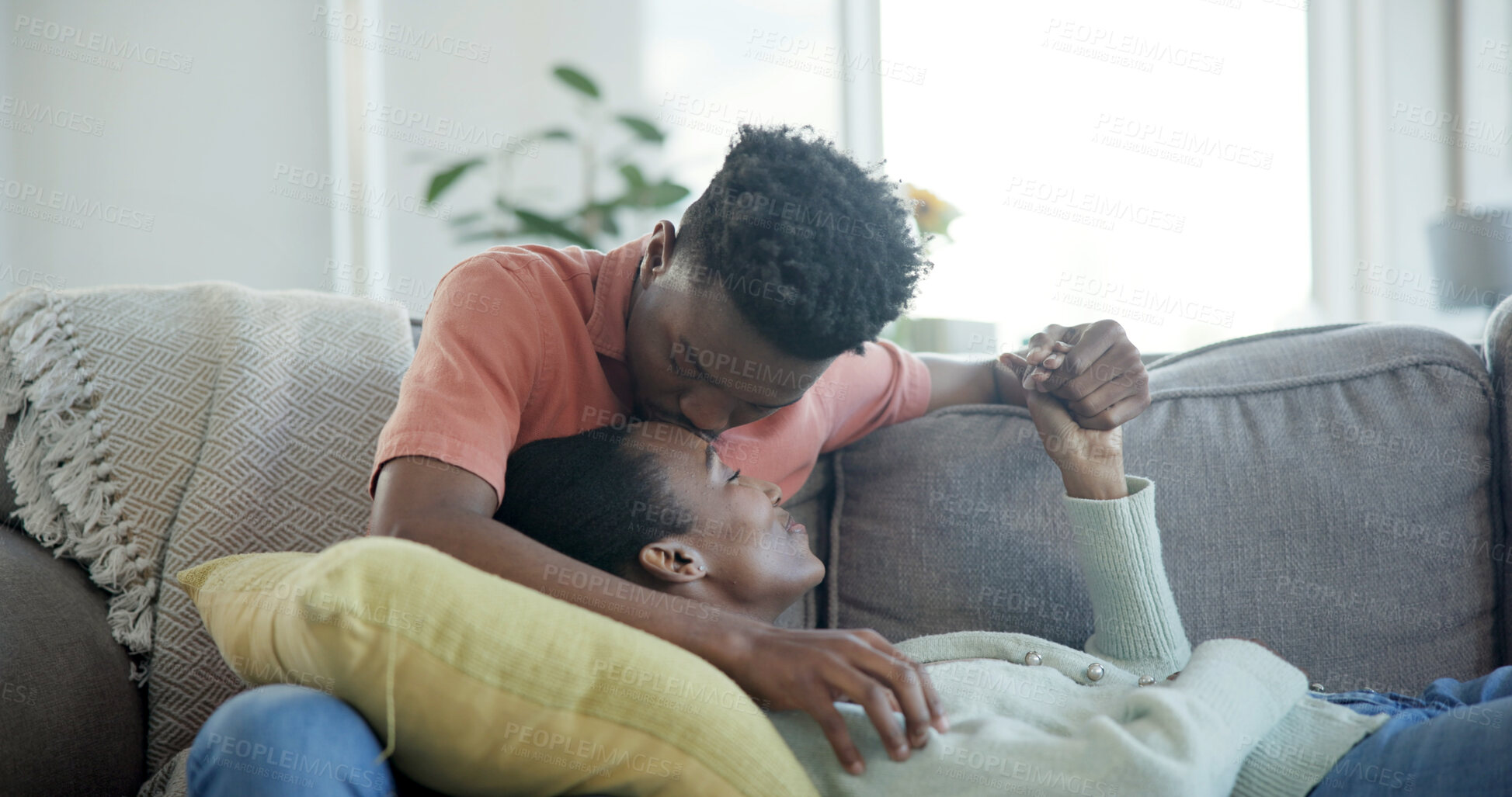 Buy stock photo Couple, relax and holding hands on couch with kiss, commitment and bonding together for connection. Happy, black people and dating with love for caring relationship, loyalty and affection in house.