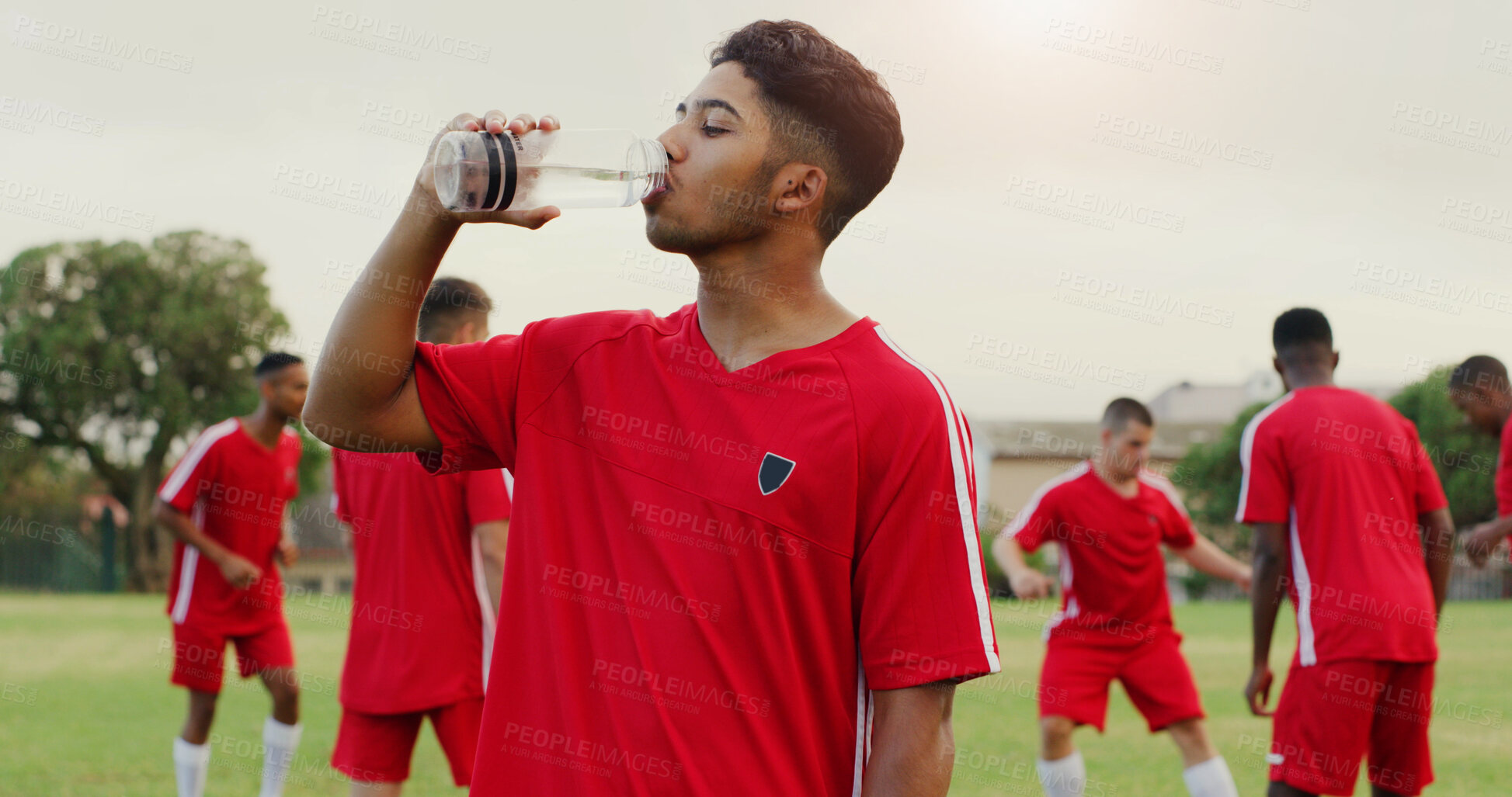 Buy stock photo Break, drinking water and soccer with man outdoor on grass pitch for fitness or hydration. Bottle, health and sports with thirsty football player on field for competition, game or match practice