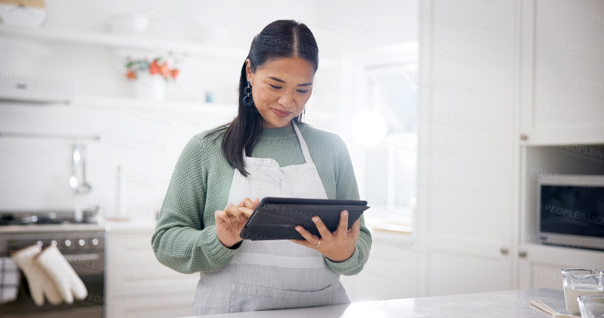 Buy stock photo Baking, reading and woman with tablet in kitchen, meal inspiration and search for cuisine tutorial. Home, smile and Asian person with tech for recipe info, check food blog and cooking hacks video