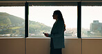 Business woman, phone and window in office building for thinking, problem solving and corporate job. Employee, technology and person waiting for communication, feedback or results for city project