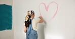 Painting, heart and back of woman by wall for home decoration, remodeling and creativity. Space, painter and person with color, shape and paintbrush for inspiration, design and diy makeover in house