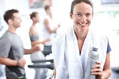 Buy stock photo Shot of a young woman in sportswear with men and women joggin on treadmills in the background