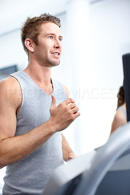 Buy stock photo Shot of a young man jogging on a treadmill in a gym