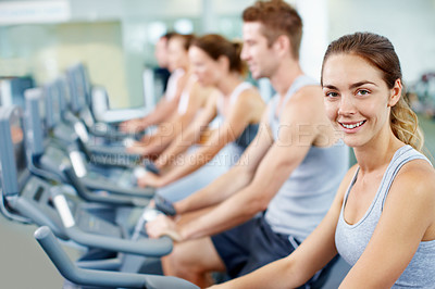 Buy stock photo Portrait of a young woman on an exercise bike at the gym