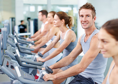 Buy stock photo Portrait of a young man on an exercise bike at the gym 