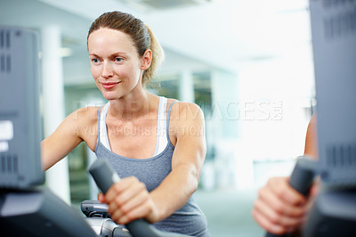 Buy stock photo Shot of a young woman on an exercise bike at the gym