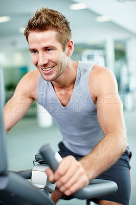 Buy stock photo Shot of a young man on a cycling machine in a gym
