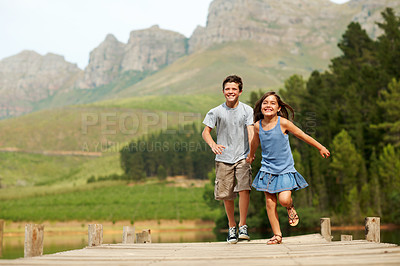 Buy stock photo Support, children and holding hands at lake, running or play game on jetty for vacation with smile. Happy kids, brother and sister on dock for summer trip, portrait and travel with care outdoor