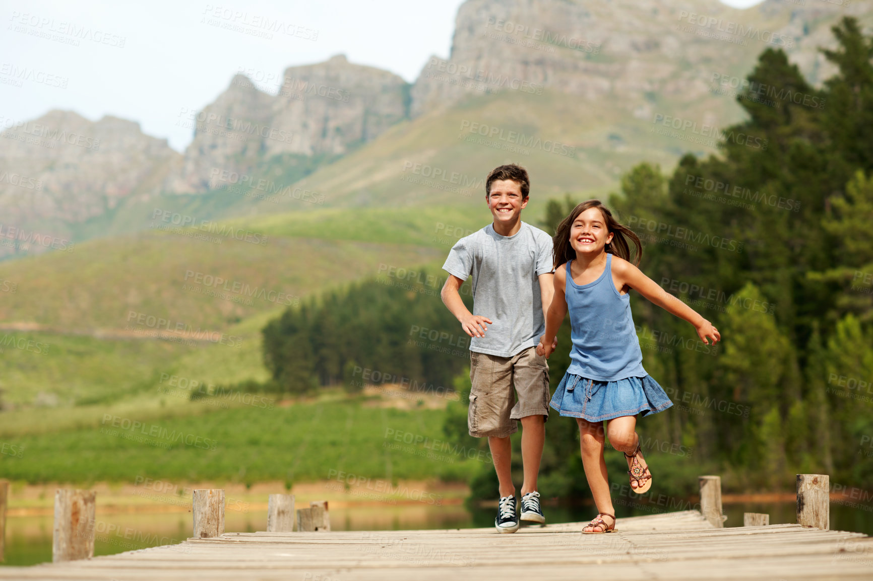 Buy stock photo Support, children and holding hands at lake, running or play game on jetty for vacation with smile. Happy kids, brother and sister on dock for summer trip, portrait and travel with care outdoor