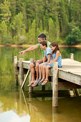 Buy stock photo Happy, father and pointing with children at lake, adventure and scenic view on holiday trip. Smile, man or hand gesture in nature with kids, wildlife observation and lakeside for sightseeing vacation