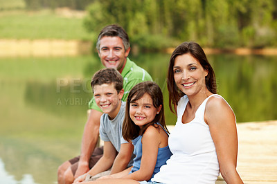 Buy stock photo Portrait, smile and family by lake for travel, together or bonding with summer vacation in nature. People, parents and kids for break, holiday and happy with relax on pier by water for connection