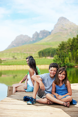Buy stock photo Children, portrait and relax on dock for holiday with countryside, bonding and smile in nature together. Family, brother and sister with jetty outdoor for vacation, summer trip and travel by lake