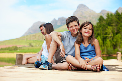 Buy stock photo Children, portrait and relax on dock for vacation with countryside, bonding and smile in nature together. Family, brother and sister with jetty outdoor for holiday, summer trip and travel by lake