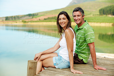 Buy stock photo Lake, portrait and relax with happy couple in nature for holiday getaway or natural scenery. Man, woman or travel with smile on lakeside bridge for outdoor weekend, summer vacation or adventure