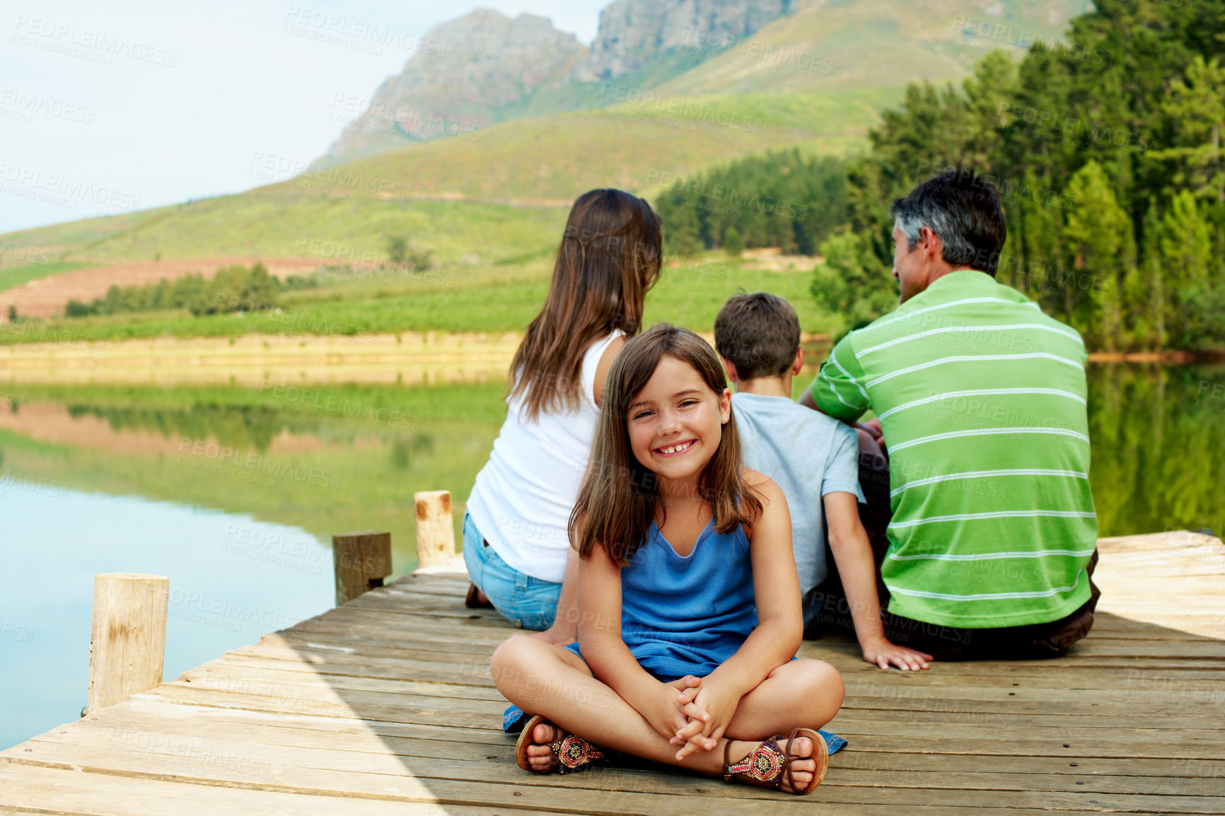 Buy stock photo Portrait, holiday and happy kid on lake dock, relax and family outdoor for summer travel. Girl, child and break at pier on vacation, countryside tourism and chill with parents by water in nature