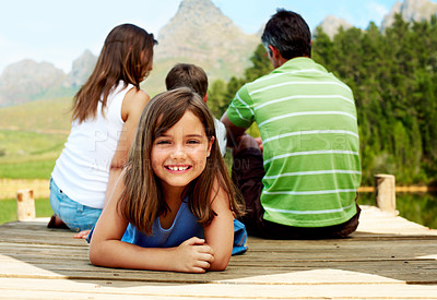 Buy stock photo Family, vacation and happy child on lake jetty, portrait and relax outdoor for summer travel. Girl, kid and rest at pier on holiday, countryside tourism and sibling with parents by water in nature