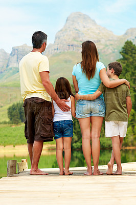 Buy stock photo Back, family and hug outdoor on lake pier for summer holiday, vacation and countryside trip. Mountains, river and love of man, woman and children in nature to relax with connection, calm or care
