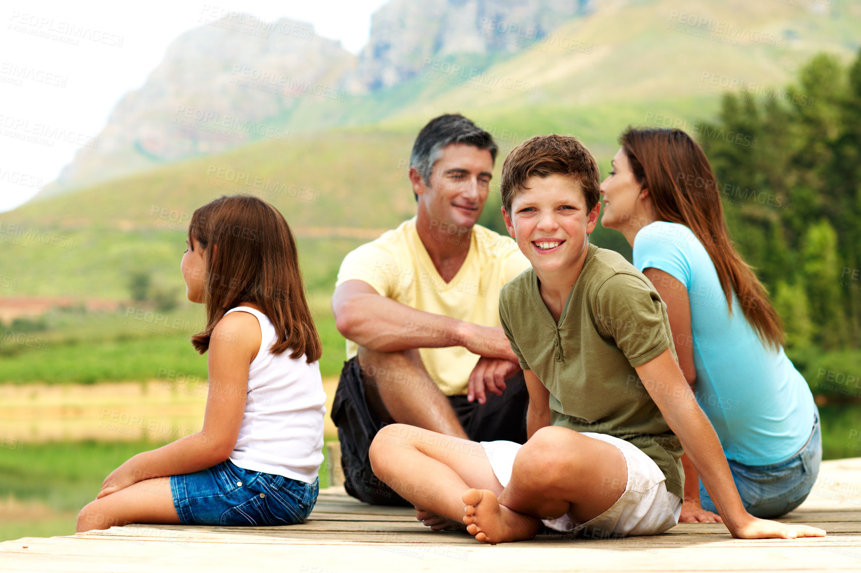 Buy stock photo Boy, smile and family on pier for travel, together or bonding with summer vacation in nature. People, parents and male kid with sister for holiday or break, relax and portrait outdoor for fresh air