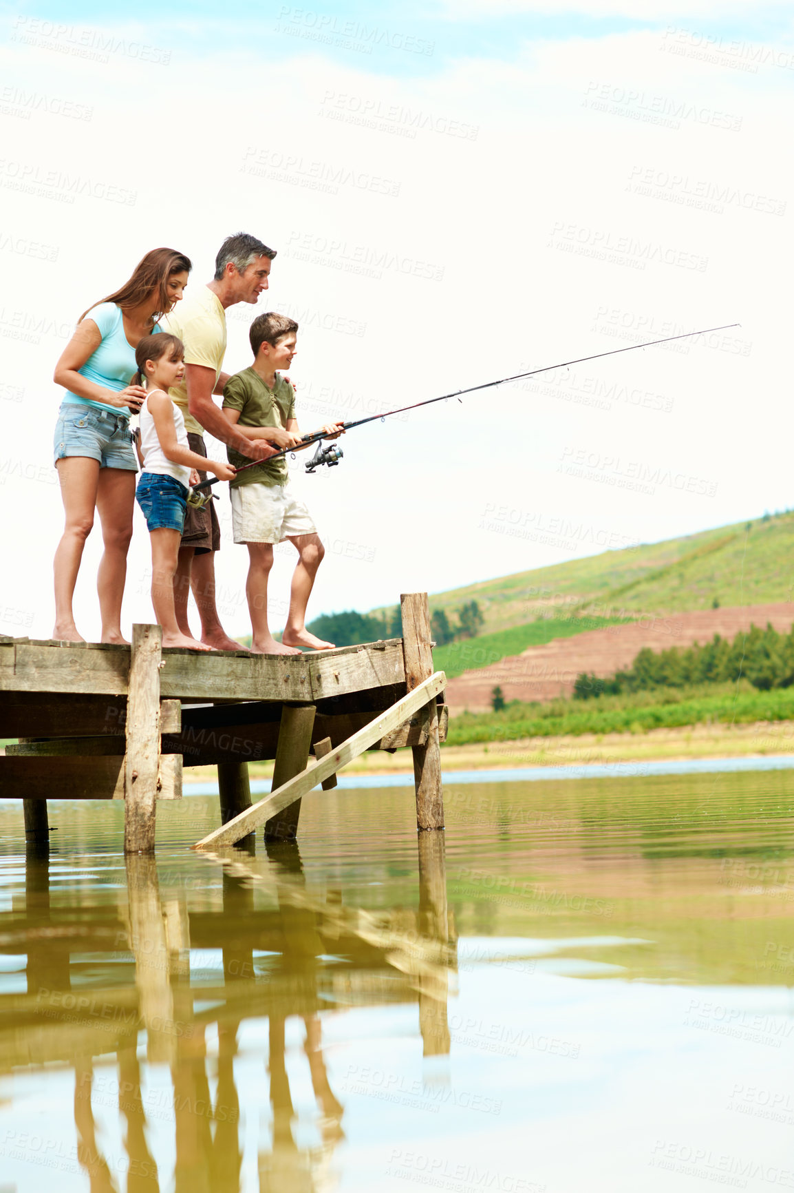 Buy stock photo Fishing, pier and parents with children by lake for summer vacation, holiday and bonding together. Family, nature and dock with mom, dad and kids for adventure, learning and catch fish on weekend