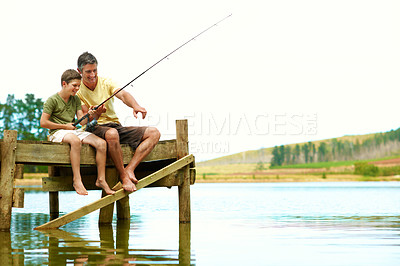 Buy stock photo Dad, child and fishing at lake pier on vacation, teaching and pointing for connection together. Happy parent, boy and rod by water outdoor for relax, learning and bonding on holiday with space