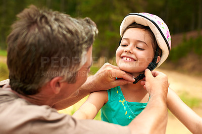 Buy stock photo Smile, father and helping child with helmet, safety and guidance for bicycle riding. Happy, man and daughter in nature with protective gear, cycling supervision and injury prevention for travel trip