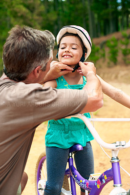 Buy stock photo Dad, help and child with bicycle helmet, safety and getting ready for ride or bonding with daughter. Outdoor, man and girl with smile on bike, development and adjusting strap for protection at park