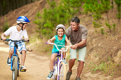 Buy stock photo Support, father or children in forest with bicycle, bonding together and guidance in summer hobby. Smile, cycling and family with help, teaching moment and parent connection for childhood development