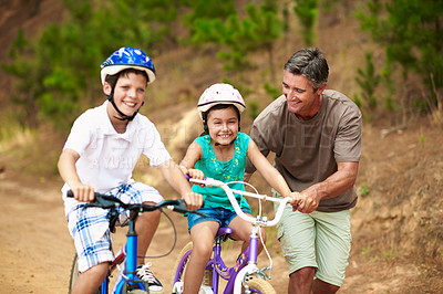 Buy stock photo Support, dad or children in nature with bicycle, bonding together and guidance in summer hobby. Smile, cycling and parent with help, teaching moment and family connection for childhood development.