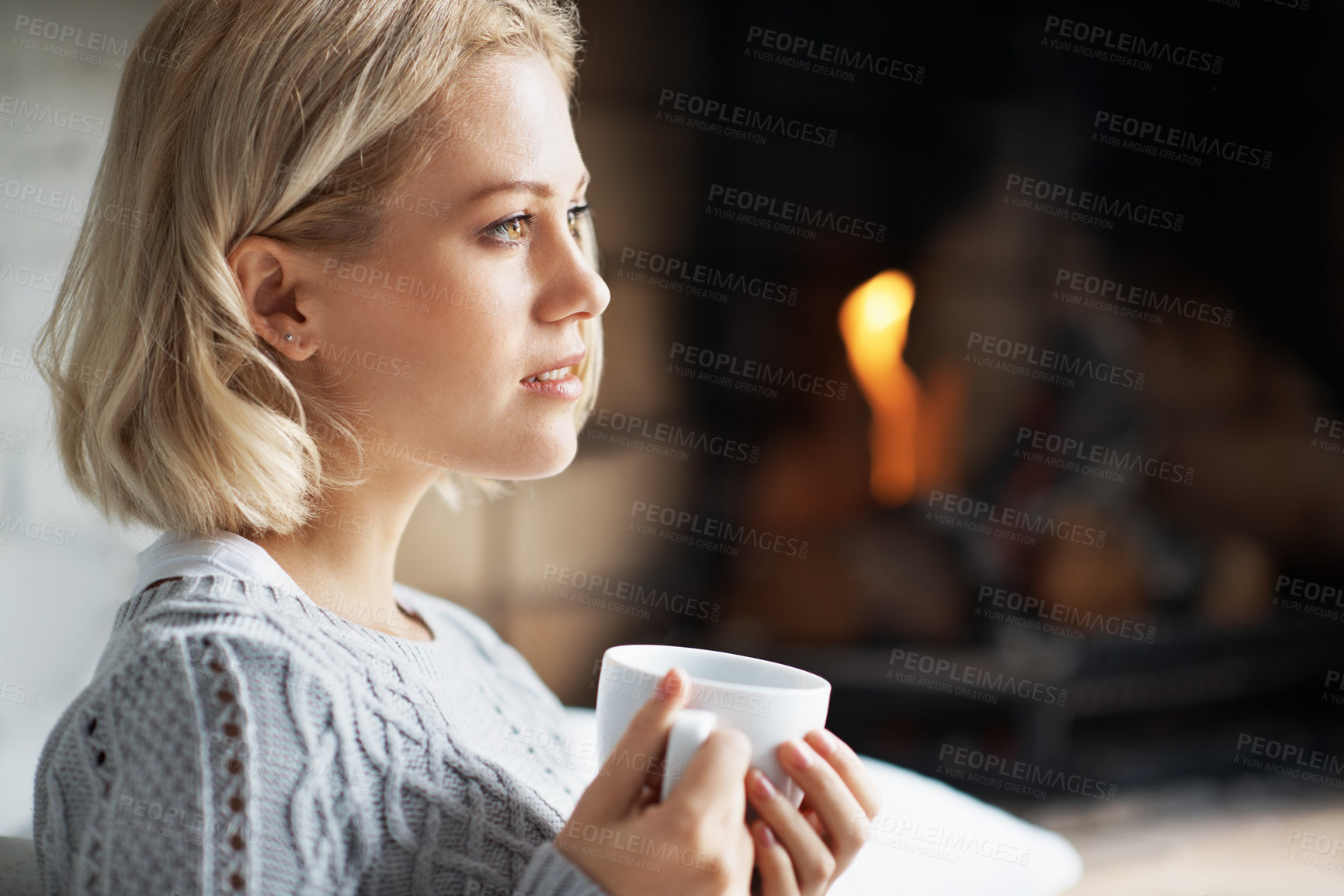 Buy stock photo Fireplace, home and woman with coffee, thinking and contemplating decision with hot drink in lounge. Remember, memory and person with warm beverage on weekend, space and reflection with tea in house