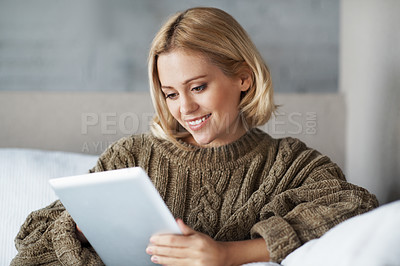 Buy stock photo A woman dressed in a cozy jersey relaxing on the couch with her digital tablet