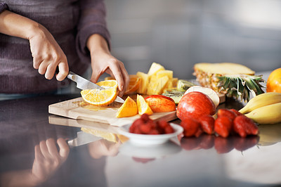 Buy stock photo A cropped shot of a woman chopping a variety of fresh fruit in her kitchen 