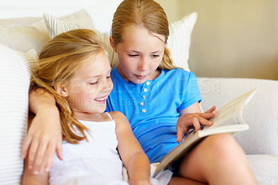 Buy stock photo Children, happy and reading book on sofa with love, bonding and care for sibling or sister in home. Girls, kids or family together for storytelling and learning, development or relax on couch