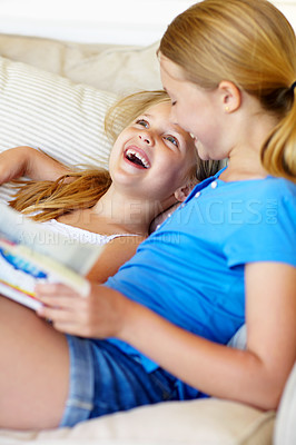 Buy stock photo Children, home and reading book on sofa with laugh, love and care for sibling or sister in lounge. Girls, kids or happy family together for storytelling and learning, development or relax on couch