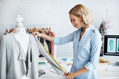 Buy stock photo A young designer measuring the sleeve of a jacket on a mannequin