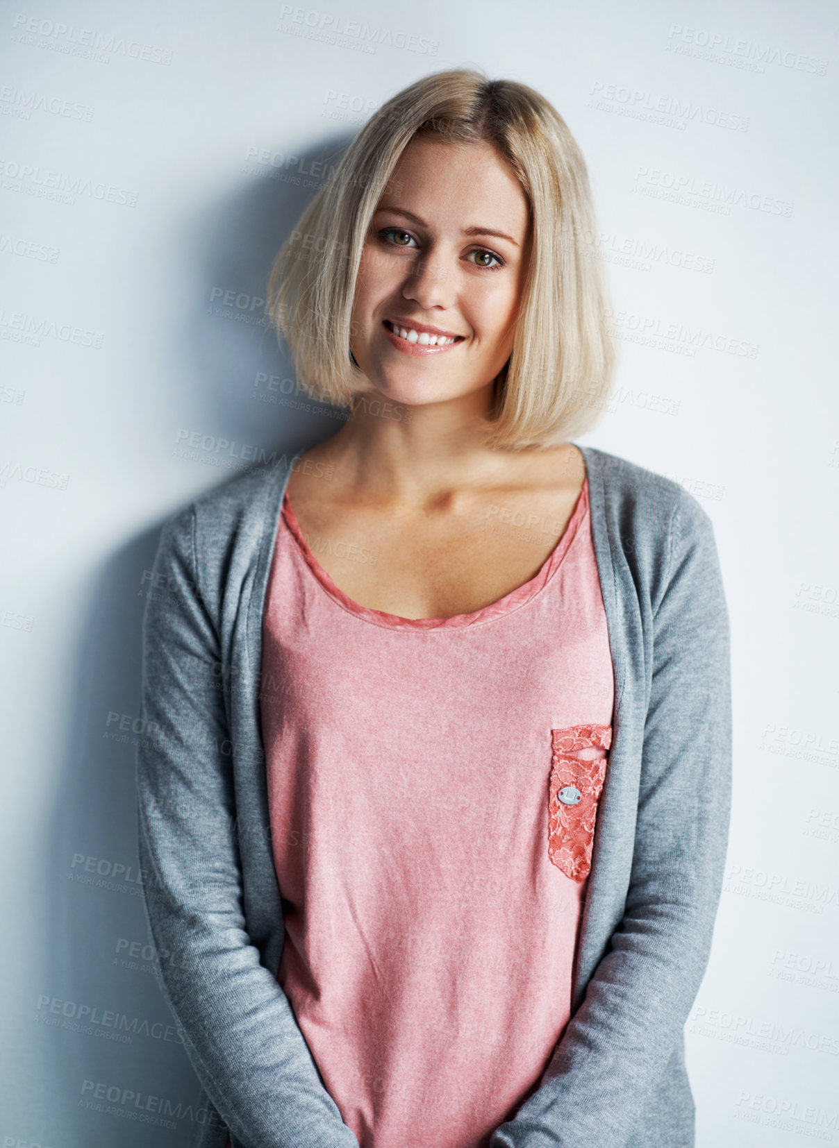 Buy stock photo Portrait of a pretty young blonde woman leaning against a white wall