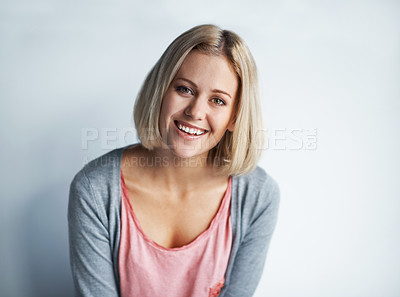 Buy stock photo Portrait of a pretty young blonde woman leaning against a white wall