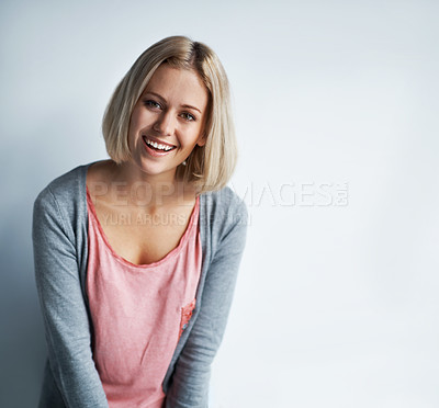 Buy stock photo Portrait of a pretty young blonde woman leaning against a white wall