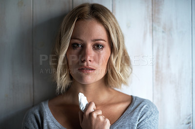 Buy stock photo Portrait of a pretty young blonde woman crying while holding a tissue