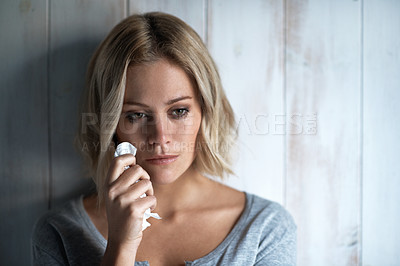 Buy stock photo A pretty blonde girl looking away while crying and holding a tissue