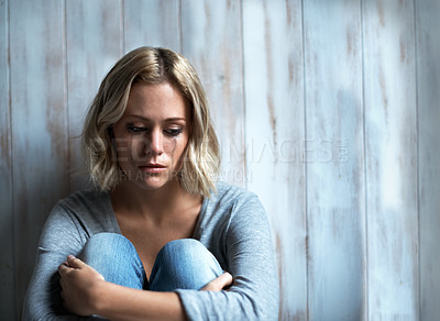Buy stock photo A young woman crying while sitting on the floor with mascara running down her face