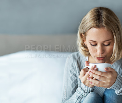 Buy stock photo A closeup of a young blonde woman blowing on a cup of hot coffee