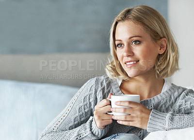Buy stock photo A young blonde woman looking away thoughtfully as she enjoys a cup of coffee at home
