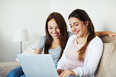 Buy stock photo Two teenage girls sharing a laptop while sitting on the couch at home